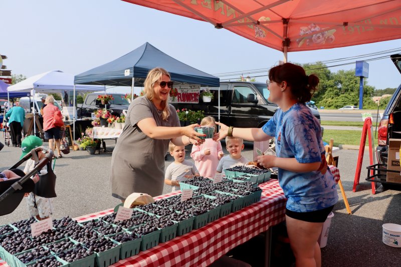 Ashley Voshell, left, buys a pint of blueberries from Bennett’s Orchards. The Voshell family made the Wednesday market a stop of the vacation in Lewes.